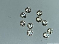 Ten loose round diamonds laid out on flat grey surface