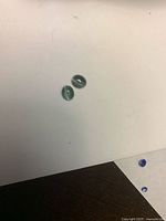 Two gray-green oval cabochons on white background