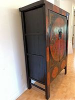 Side view of black lacquered cabinet showing overall form and wear