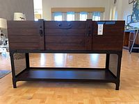 Front view of wood trunk console table showing lift-top chest, metal frame, lower shelf