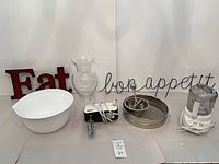 All eight items arranged: processor, mixer, bowl, food mill, strainer, vase, red and wire signs