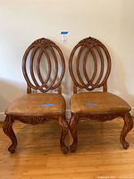 Front view of both carved wood armless chairs showing overall design, upholstery and condition