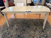 Full view of off-white rectangular dining table on rug