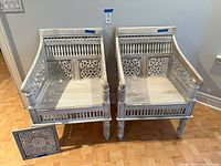 Front view of both carved armchairs with wall panel leaning in front