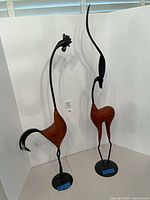 Front view of two tall wood and metal animal sculptures on round bases