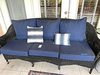 Black wicker sofa with blue striped cushions and pillows