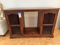 Front view of wood console showing two slatted doors and open center