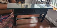 full view of console table with glass top showing three drawers and stretcher base