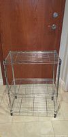 Full view front of chrome wire rack showing three shelves and casters