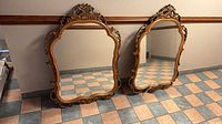 Front view of both matching Rococo wall mirrors leaning against wall