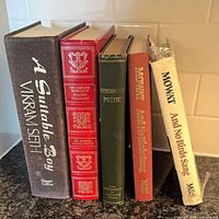 Five upright books displaying spines including A Suitable Boy, Franklin Library red leather, Representative Poetry, Mowat hardcover, Mowat dust jacket