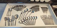 Drawer view of entire flatware set showing spoons, forks, knives, and serving pieces