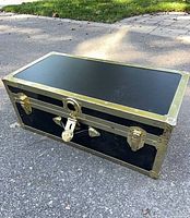 Full view of closed black Everlite trunk showing brass-tone hardware and reinforced corners