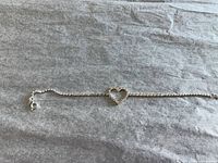 Full view of bracelet laid flat showing heart charm and clasp