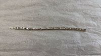 Full view of silver-tone tennis bracelet laid flat