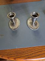 Two matching silver-tone candlesticks on table