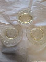 Two round plates and matching ashtray displayed on fabric