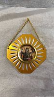Front of gold-tone metal medallion showing radial cutouts and central Madonna and Child image with chain