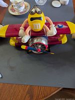 Full view of M&M's airplane dispenser front with yellow figure on fuselage and propeller visible