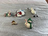 Group view of four enamel snowman brooches and one pearl pin