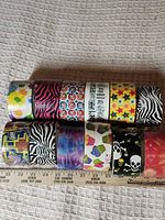 All 12 decorative duct tape rolls side view showing patterns and relative sizes with ruler for scale