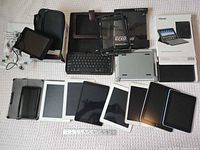 Front view of all tablets, keyboard, cases, cables and earbuds laid out on surface