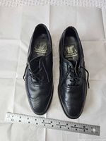 Top view of both shoes showing brand insole, lace configuration, brogue detailing, ruler for scale