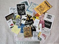 Overview of approximately 20 assorted zines spread out with ruler for scale