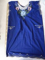 Front view of blue embroidered tunic dress with ruler for scale