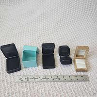 Five presentation boxes lined up with ruler for scale