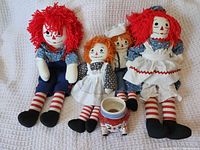 Front view of four dolls and ceramic jar
