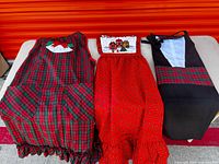Three aprons laid out: plaid, red print, black tuxedo style
