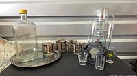 All items grouped: Gordon’s bottle on tray, Laurel & Hardy tumblers, Heineken mugs, coaster set with holder, fluted glasses, shot glasses