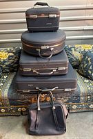 All five luggage pieces stacked: train case, hatbox, medium suitcase, large suitcase, soft tote