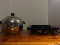 Fondue pot with lid beside electric heating base