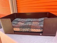 Overall view of brown plastic pet bed and patterned cushion