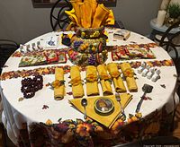 Overall view showing tablecloth, ceramic fruit baskets, various napkins, napkin rings, coasters and utensils arranged on table