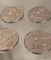 Four silver-tone 50-cent coins, obverse side visible