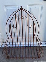 Full view of arched iron plant hanger against door