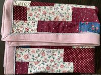 Quilt folded showing pink border and variety of patch fabrics