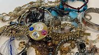 Pile of assorted jewelry highlighting pendant watch and mixed chains