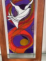Close view of stained glass showing dove and swirl pattern in teak frame