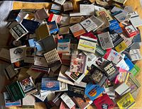 Pile of assorted matchbooks showing variety of designs and venues
