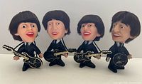 Group shot of all four Remco Beatles dolls each holding its respective instrument