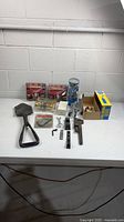 All items on table including folding shovel, locksets, Protecto box, dumbbells and hand tools
