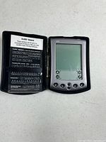Palm M500 PDA seated in open black case with Graffiti stickers visible