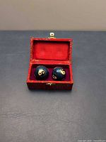 Open brocade box showing two blue yin-yang Baoding balls
