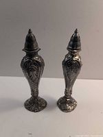 Front view of both shakers showing ornate design and silver-tone finish