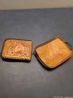 Front view of both leather items: tooled wallet and zip pouch