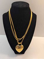 Front view of necklace on display bust showing heart pendant and multi-strand chains